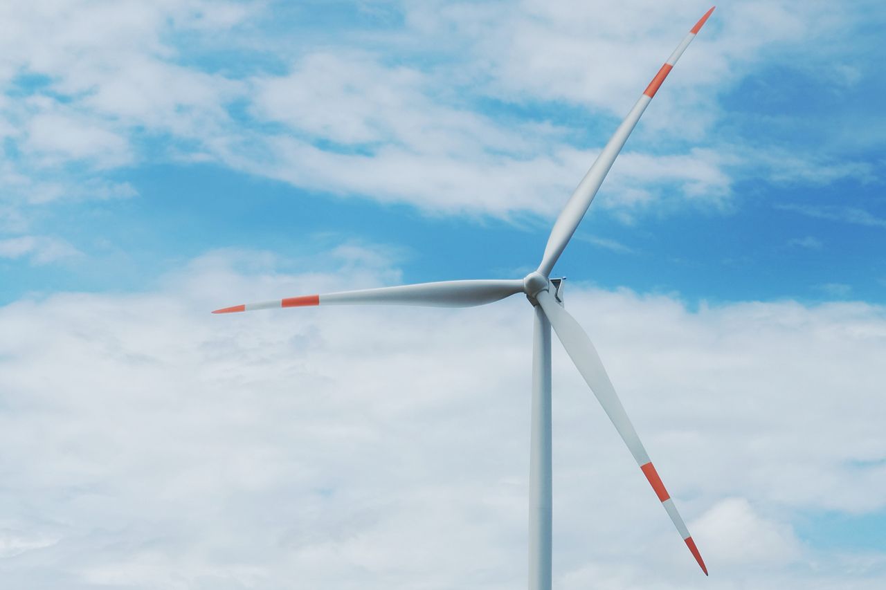 A wind turbine under a clear blue sky representing renewable energy solutions.