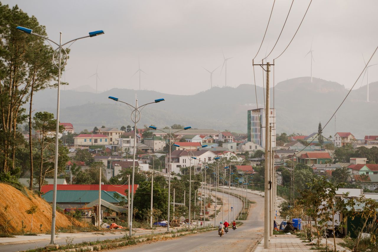 Idyllic town street with modern streetlights, surrounded by hills and wind turbines, creating an eco-friendly atmosphere.