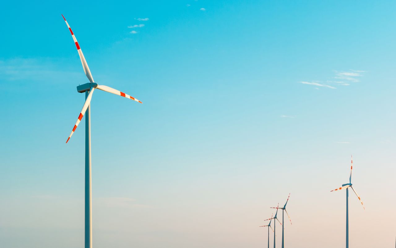A serene image of wind turbines against a bright blue sky, symbolizing sustainable energy.